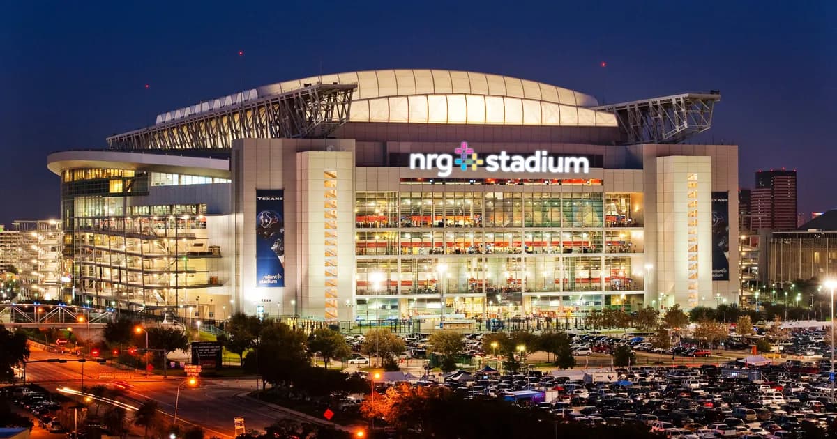 NRG Stadium in Houston, Texas A night view of NRG Stadium in Houston, Texas, its glass facade lit up beneath a curved retractable roof, with the illuminated nrg stadium sign on the front. Cars fill the surrounding lots as the city glows behind.